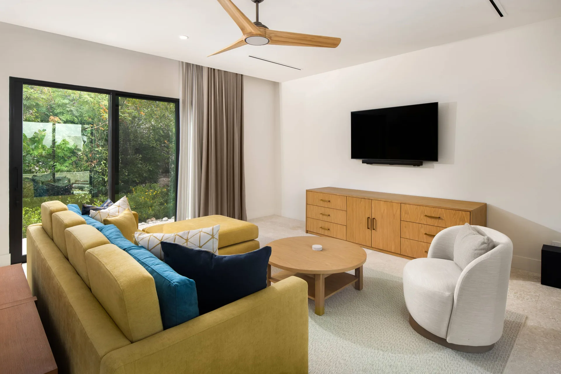Media room with yellow sofa and wall-mounted TV at The Strand Turks and Caicos.