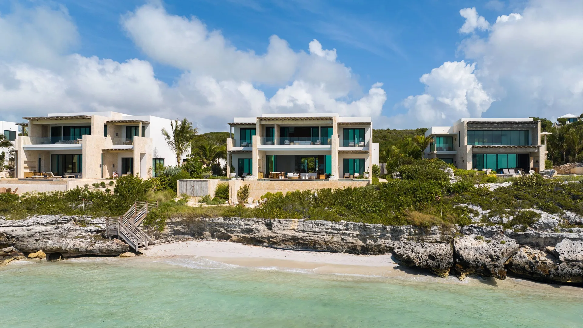 Oceanfront residences above a rocky shoreline at The Strand Turks and Caicos.