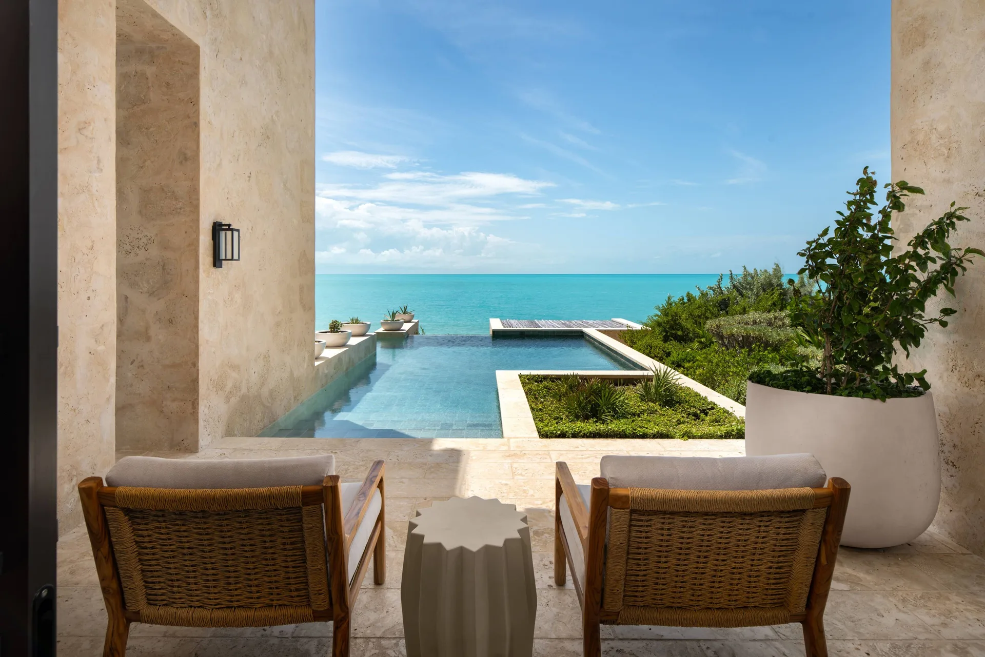 Covered terrace with two chairs, plunge pool, and ocean view at The Strand Turks and Caicos.