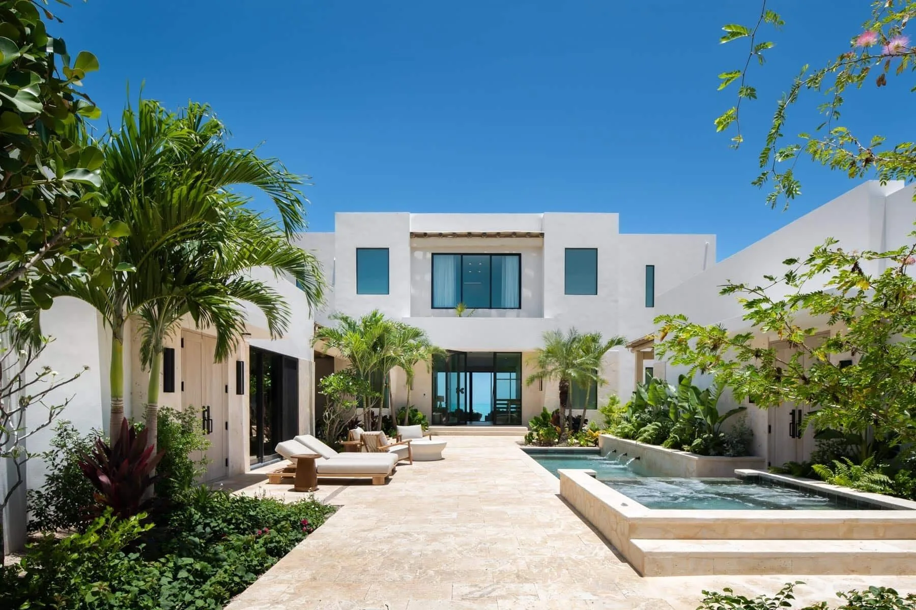 Courtyard pool with loungers and white residence exterior at The Strand Turks and Caicos.