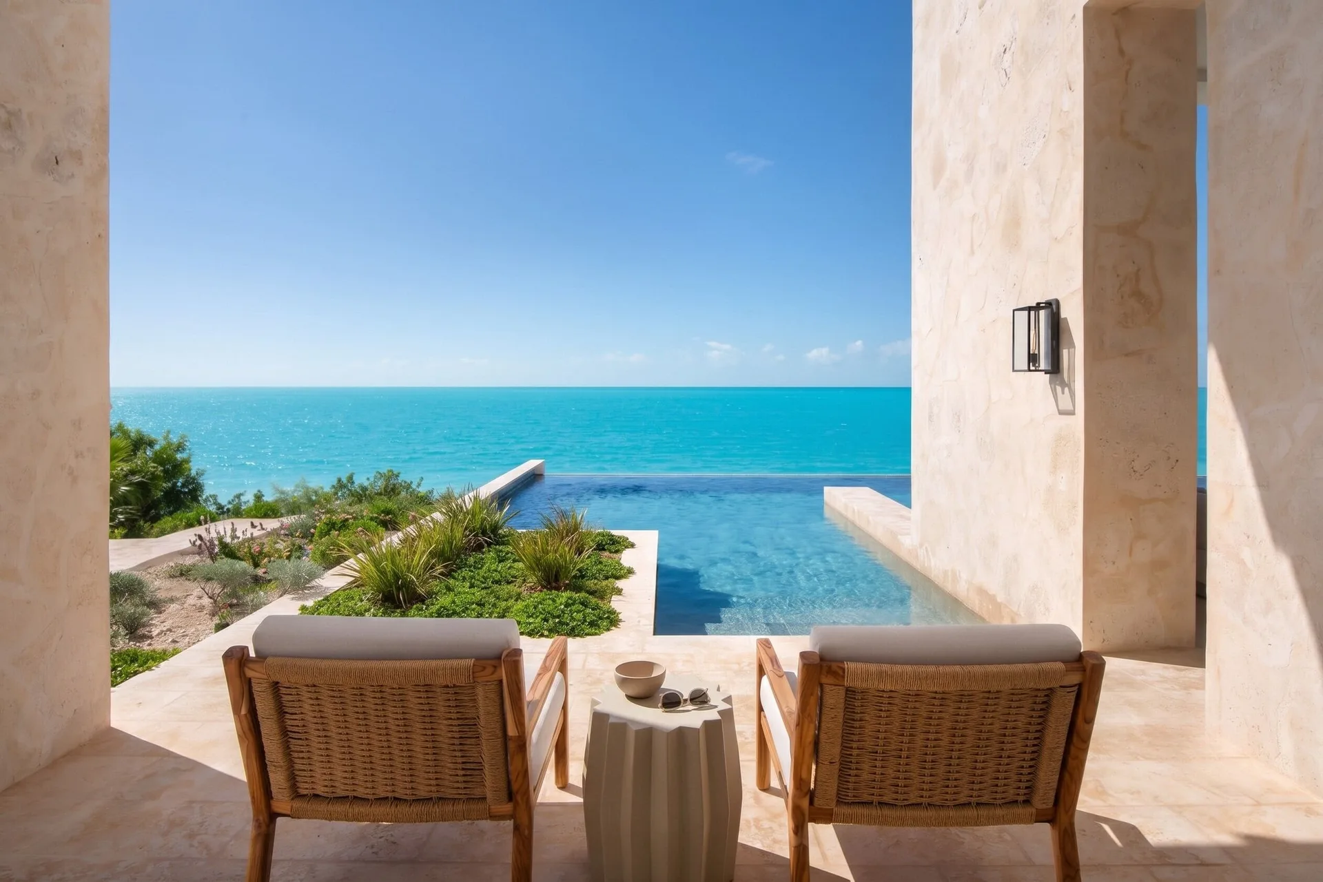 Covered terrace with two chairs facing the pool and ocean at The Strand Turks and Caicos.