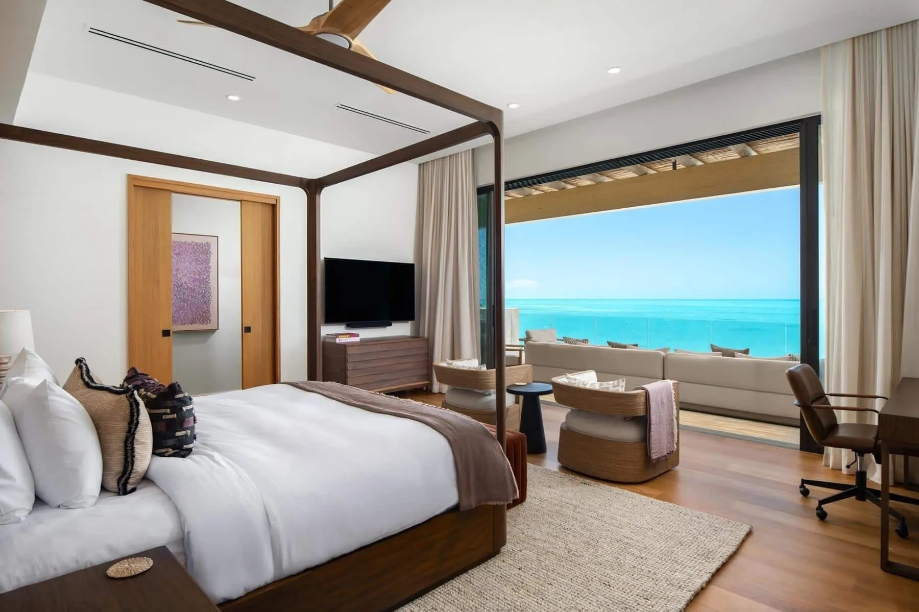 Four-poster king bedroom with wide ocean-facing doors at The Strand Turks and Caicos.