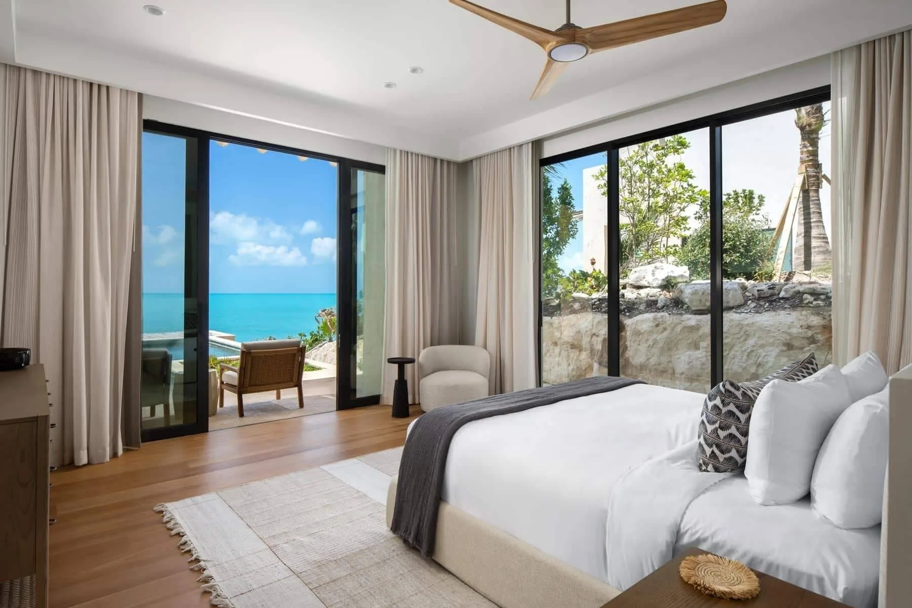King bedroom with ocean-view balcony doors and garden windows at The Strand Turks and Caicos.