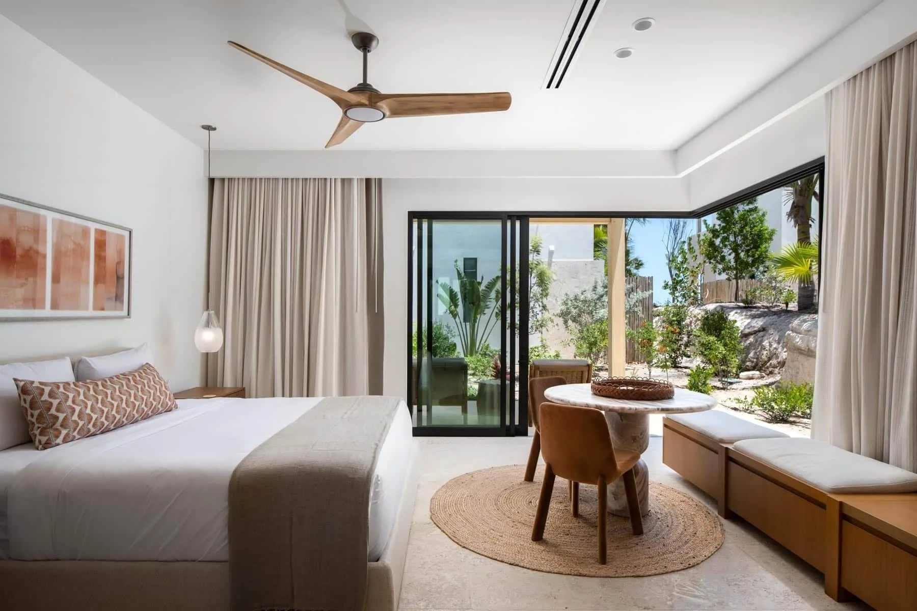 King bedroom with garden-facing windows and a round table at The Strand Turks and Caicos.
