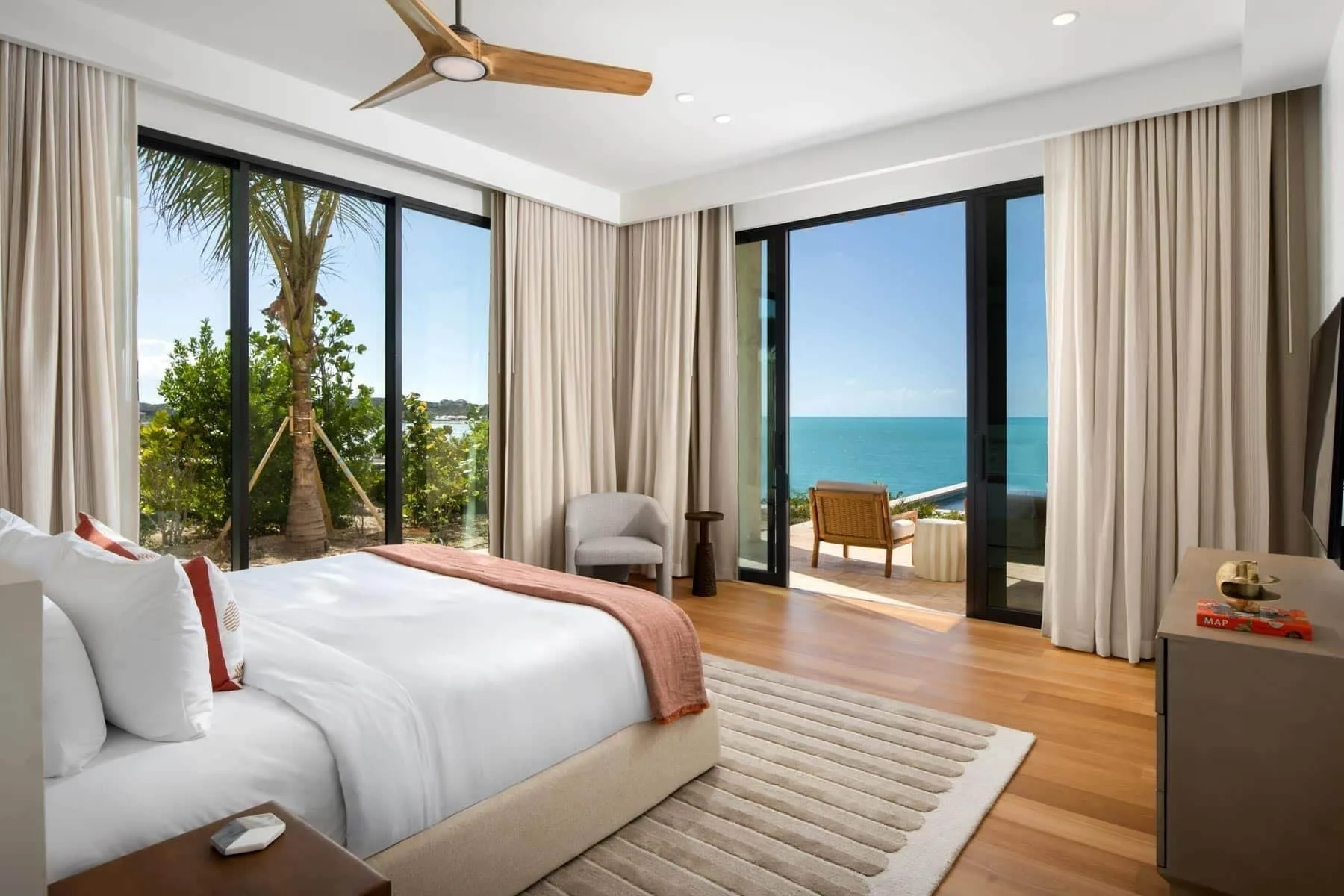 King bedroom with glass doors to an ocean-view terrace at The Strand Turks and Caicos.