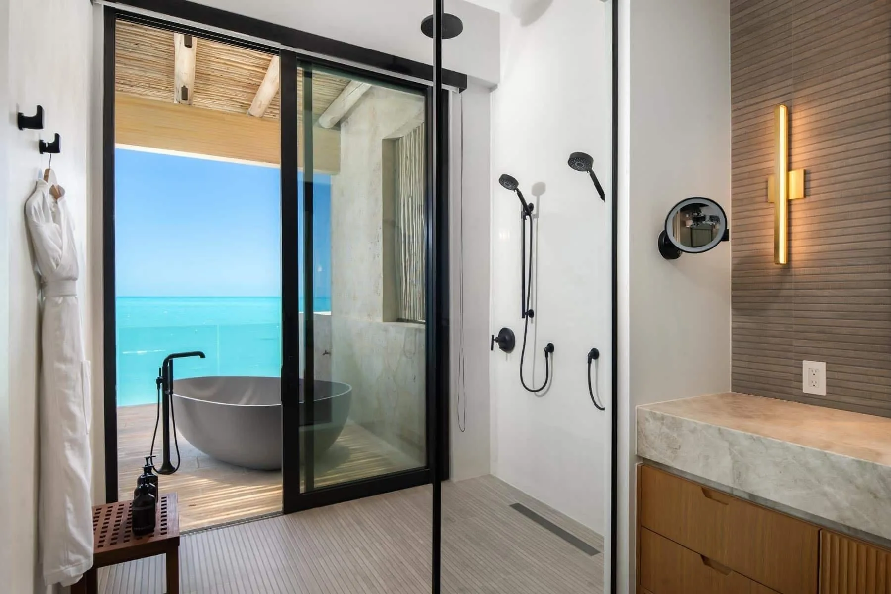 Bathroom with walk-in shower and ocean-facing tub at The Strand Turks and Caicos.