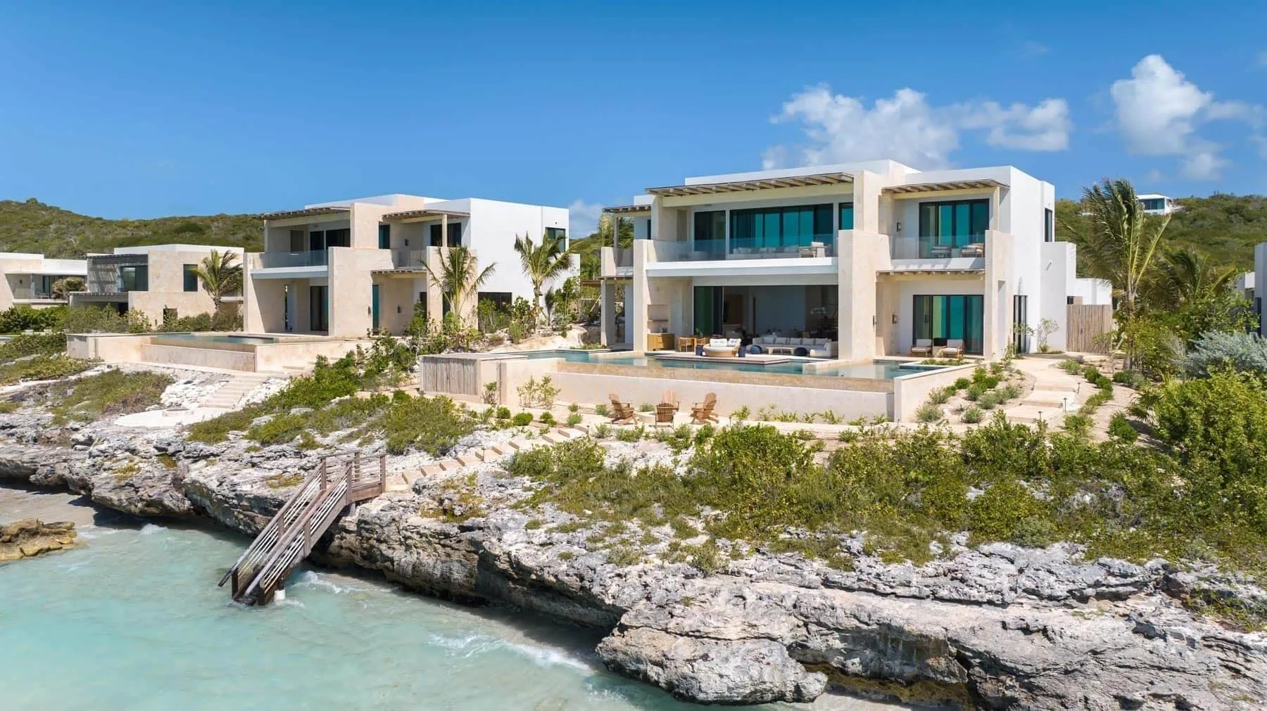 Oceanfront grand residence exterior on rocky shoreline at The Strand Turks and Caicos.