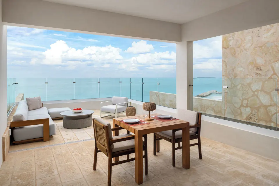 Second-floor suite terrace with seating, dining area and wide ocean view at The Strand Turks and Caicos.
