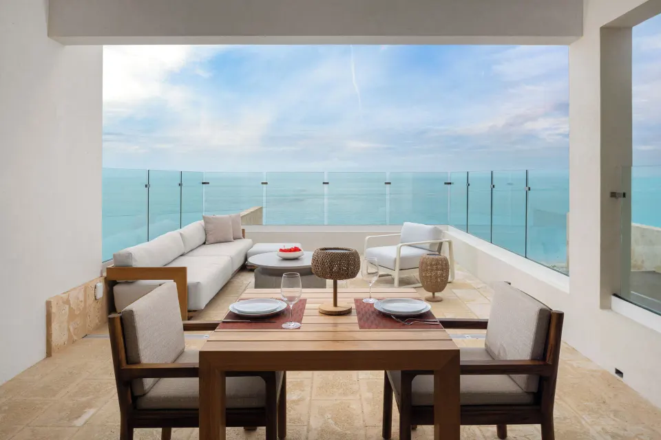 Second-floor suite terrace with dining table, lounge seating and ocean view at The Strand Turks and Caicos.