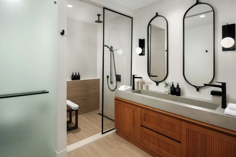 Third-floor suite bathroom with double vanity and glass shower at The Strand Turks and Caicos.