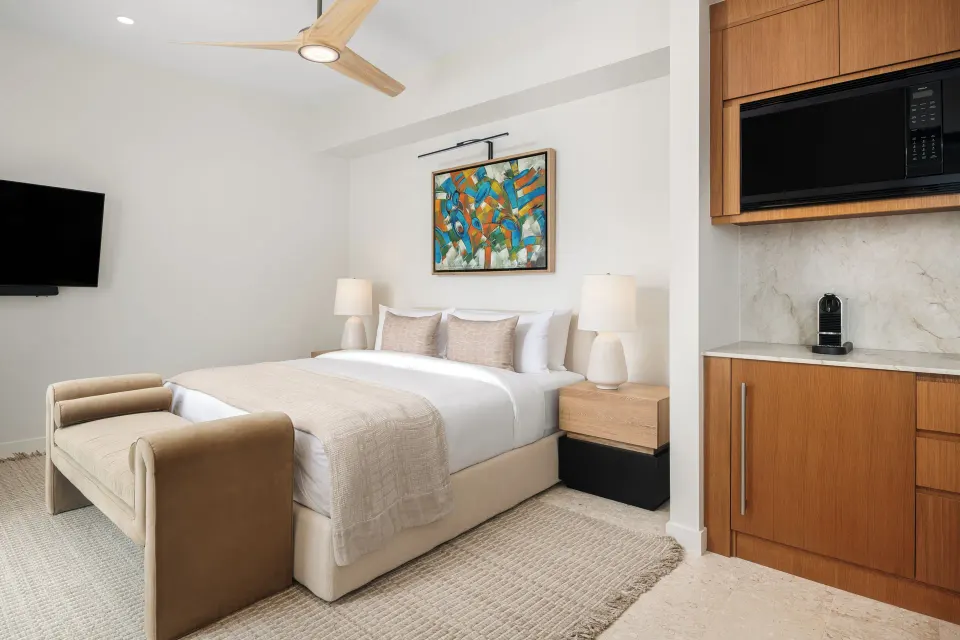 Third-floor suite king bed beside kitchenette cabinetry at The Strand Turks and Caicos.