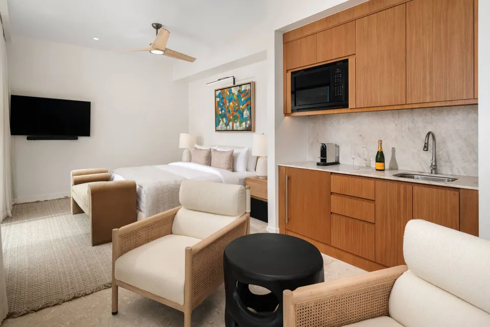 Third-floor suite with king bed, seating area and kitchenette at The Strand Turks and Caicos.