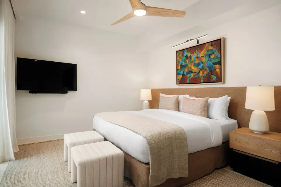 Third-floor suite king bed with TV and bedside lamps at The Strand Turks and Caicos.