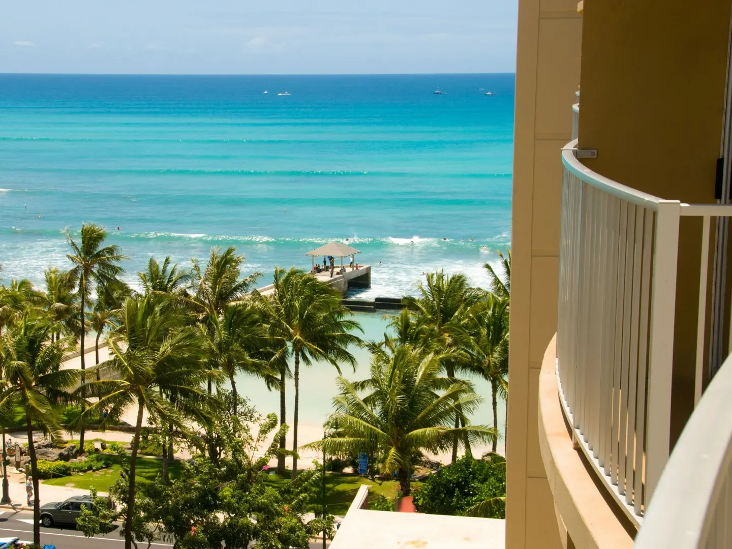Balcony view at The Twin Fin Hotel overlooking palms, Waikiki Beach, and bright blue ocean.