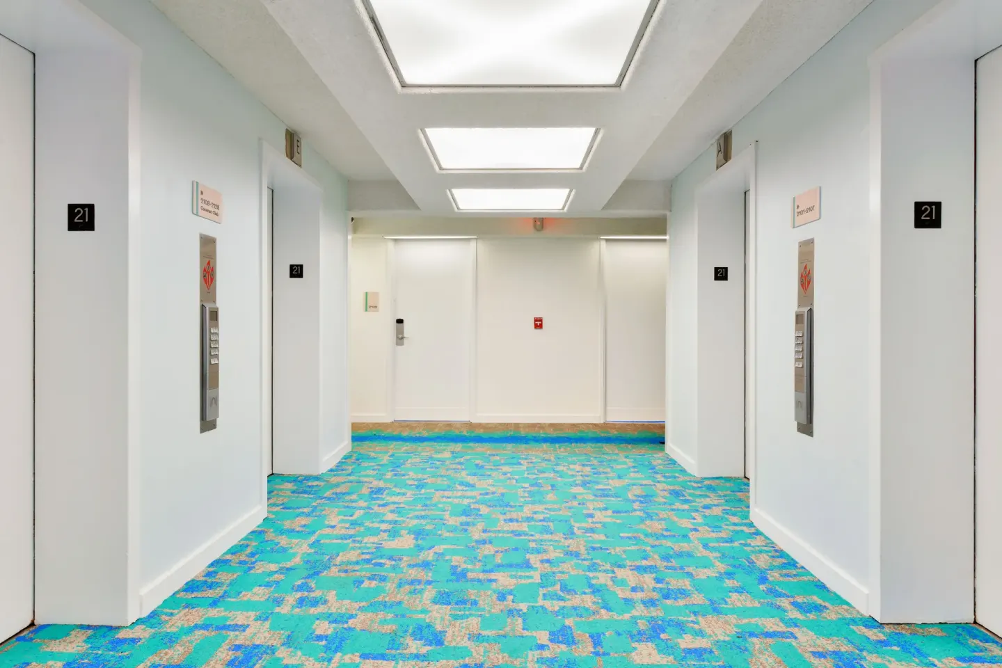 Elevator lobby with turquoise carpet on floor 21 at The Twin Fin Hotel.