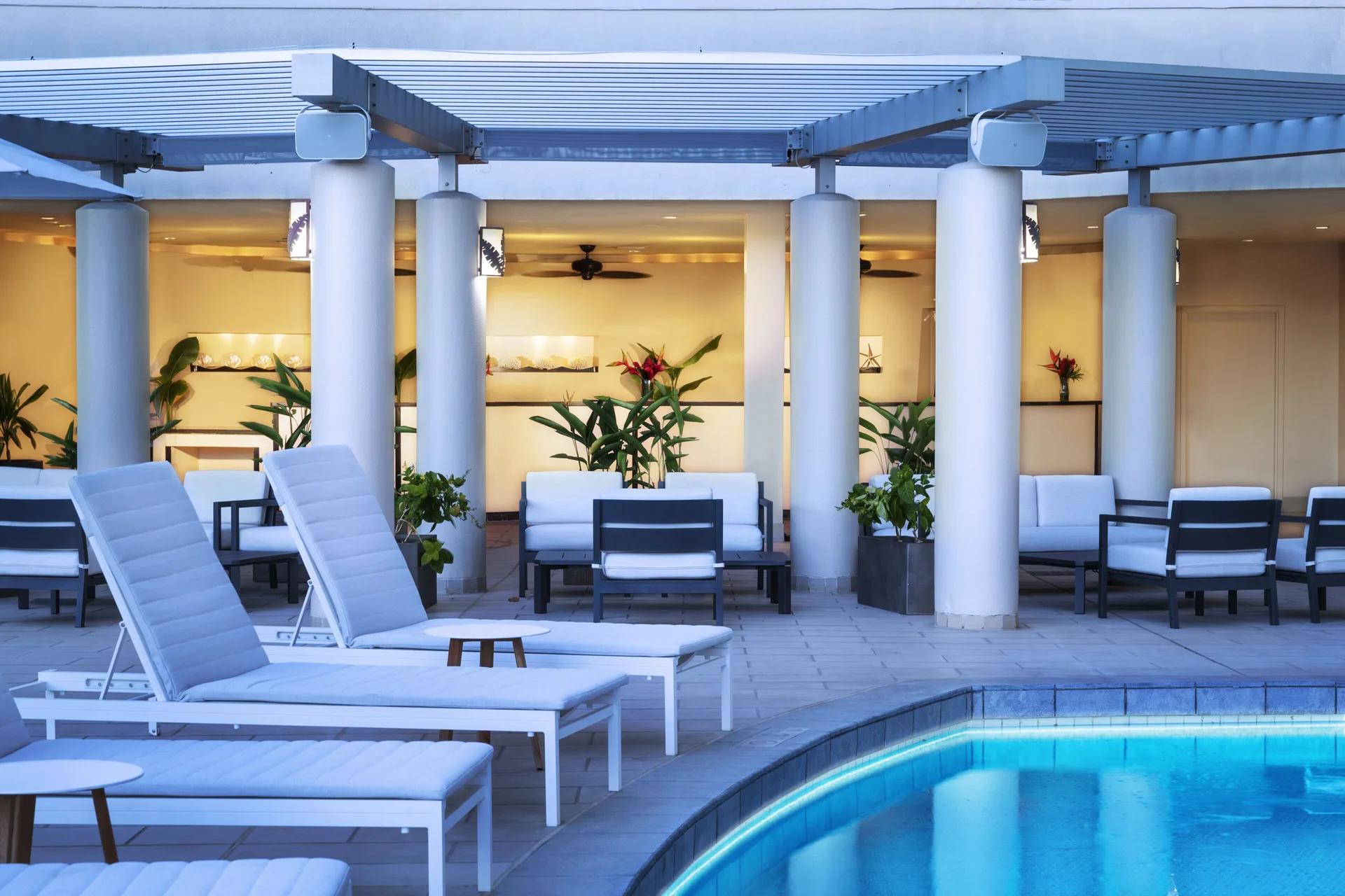 Evening pool deck with loungers and covered seating at The Twin Fin Hotel.