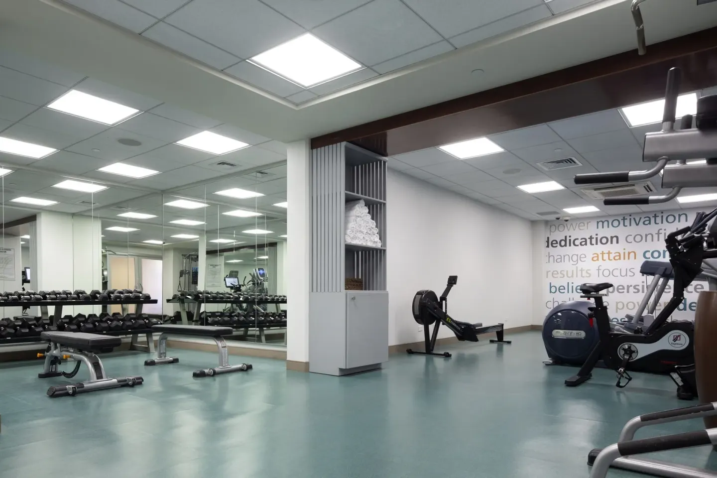 Fitness room with dumbbells, benches, and cardio machines at The Twin Fin Hotel.