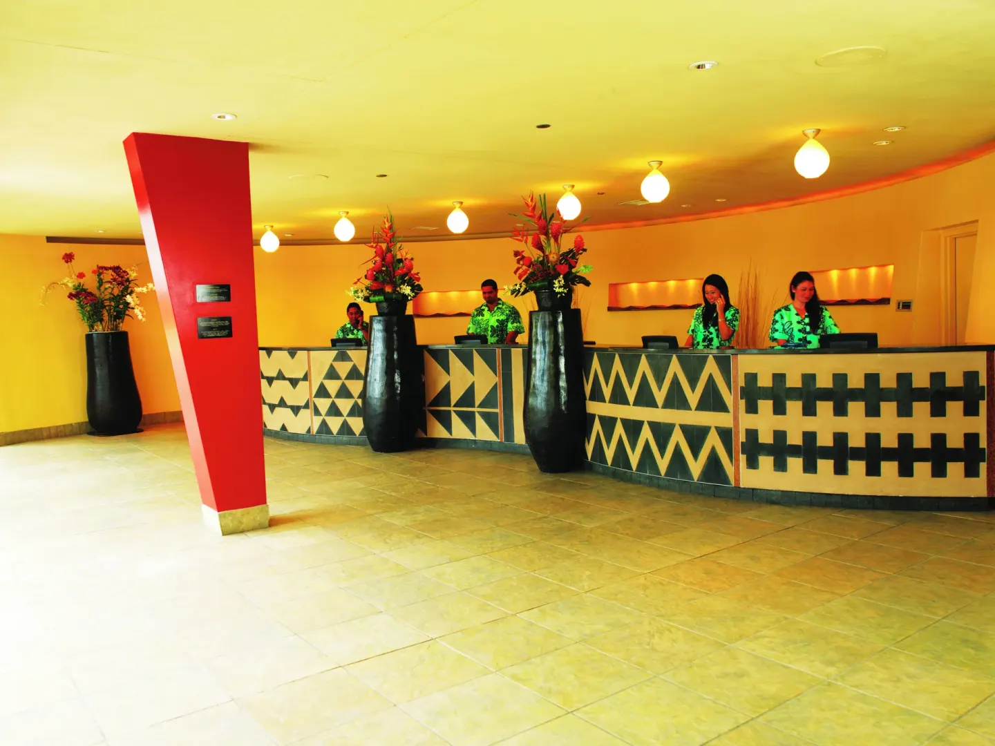 Front desk with patterned counters and floral arrangements at The Twin Fin Hotel.