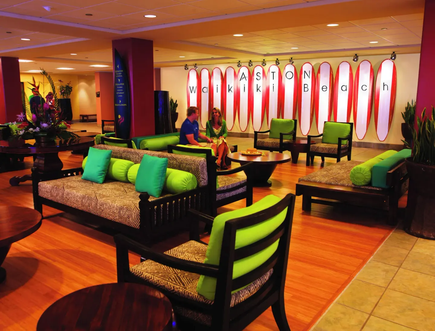 Lobby lounge with green cushions and surfboard wall at The Twin Fin Hotel.