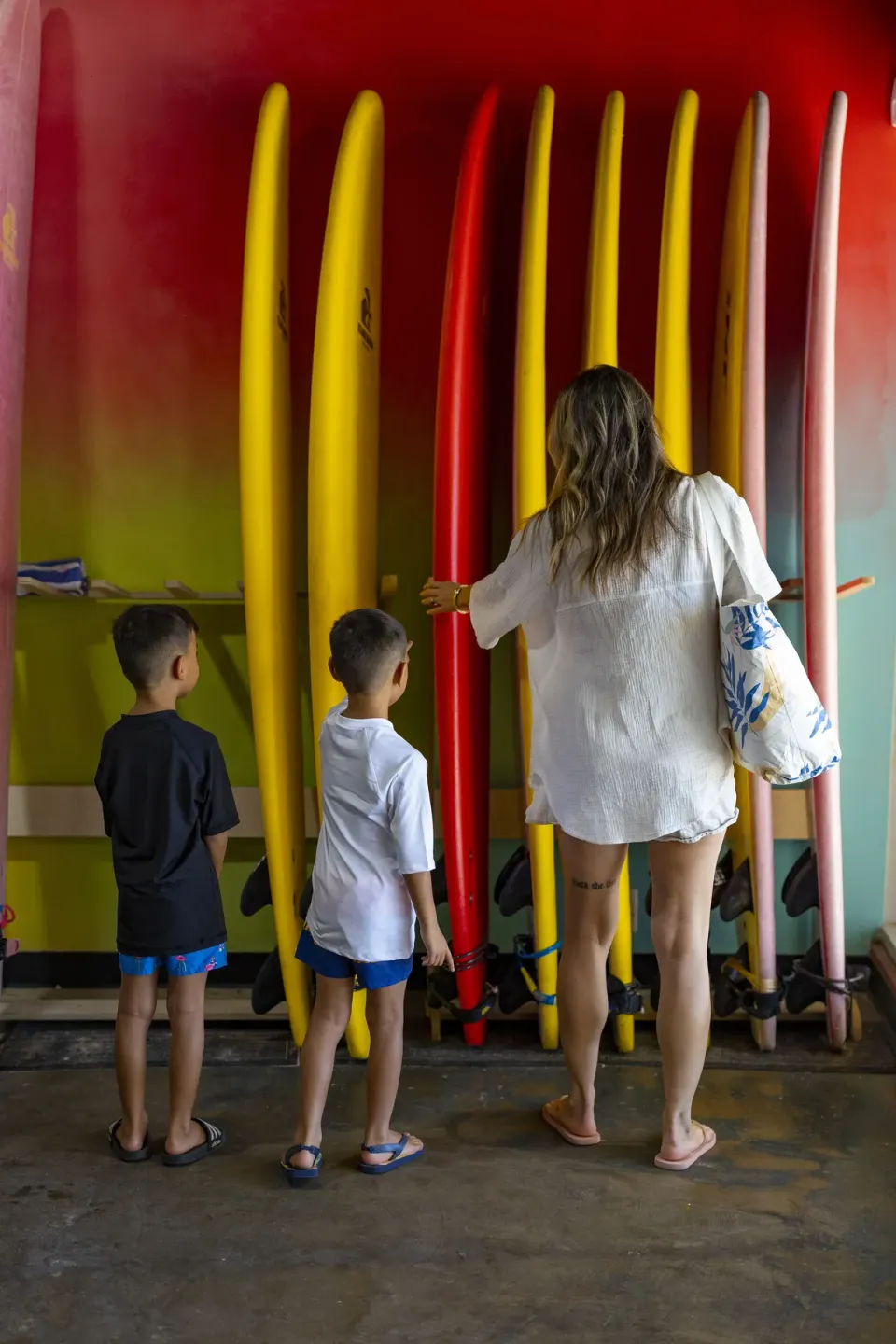 Family selecting colorful surfboards indoors at The Twin Fin Hotel.