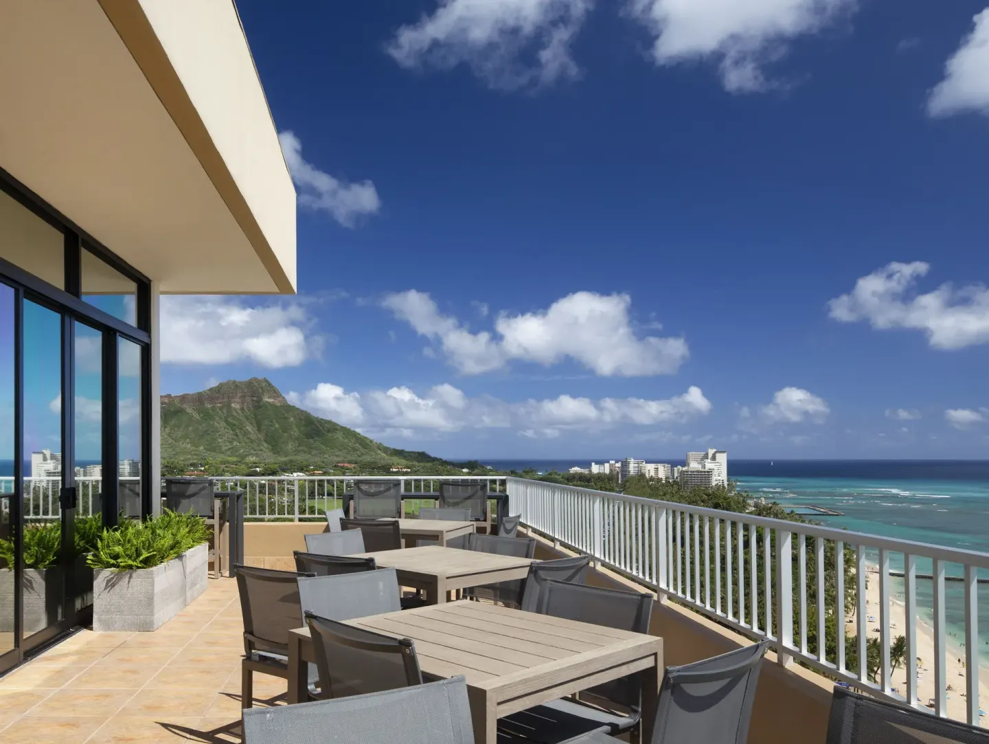 Outdoor terrace with dining tables, ocean, and Diamond Head views at The Twin Fin Hotel.