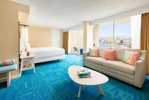 Aloha Suite Ocean View guest room with king bed, lounge sofa, and wide windows at The Twin Fin Hotel.