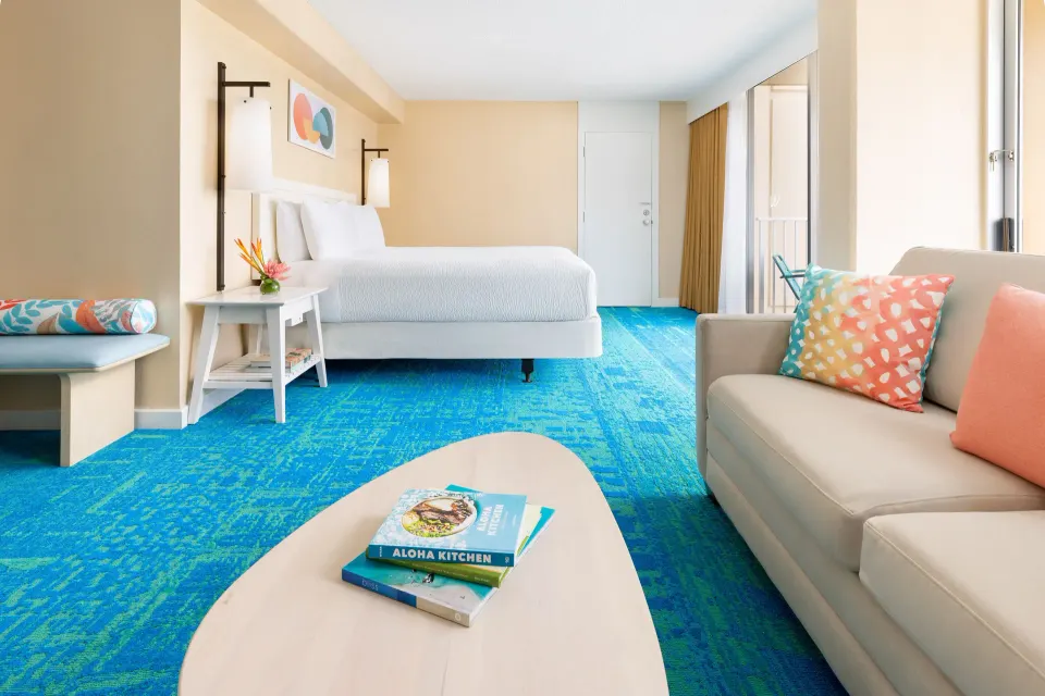 Junior Suite Ocean View at The Twin Fin Hotel with king bed, sofa, coffee table, and blue carpet.