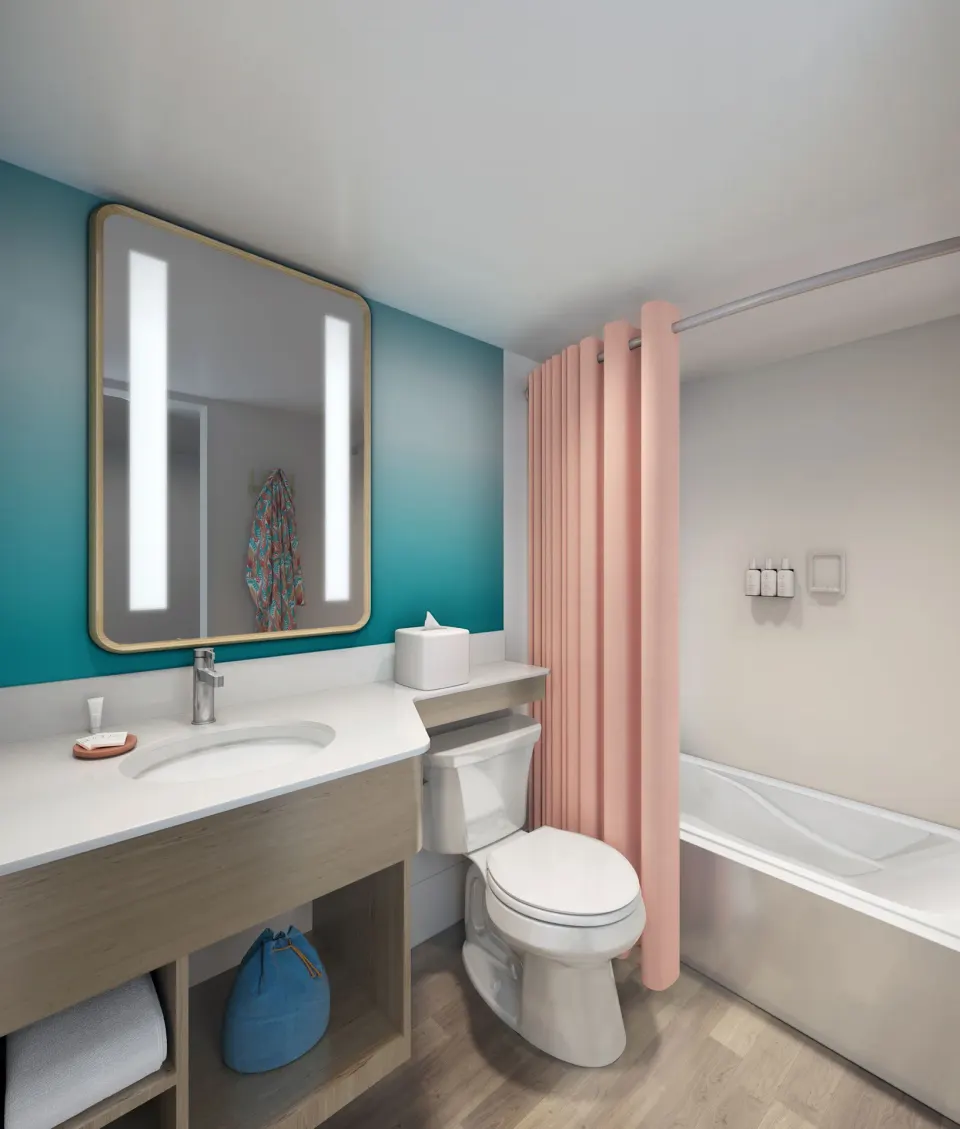 Bathroom vanity, toilet, and bathtub with pink shower curtain at The Twin Fin Hotel.