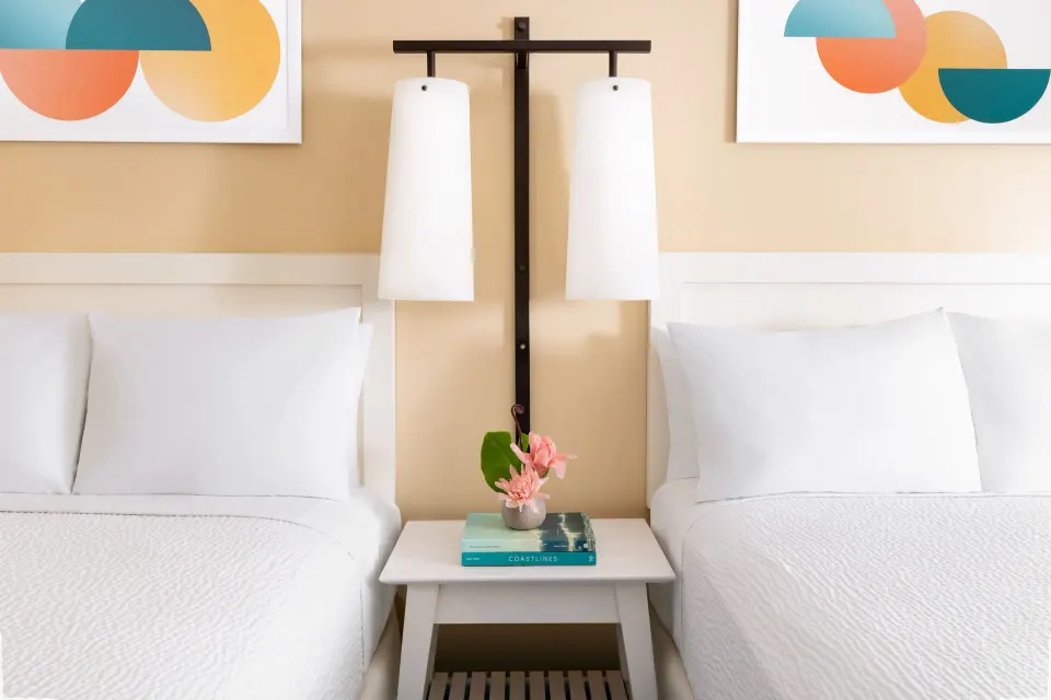 Two beds divided by a nightstand and twin lamps in a City View room at The Twin Fin Hotel.
