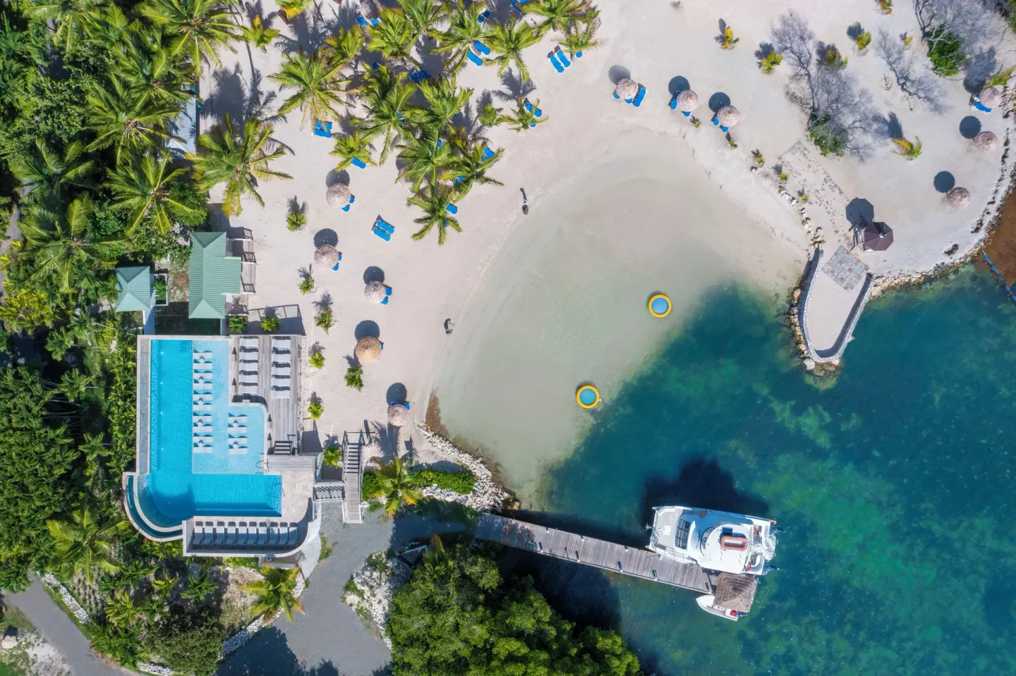 Aerial view of the beach, pool, pier and turquoise water at The Verandah Antigua.