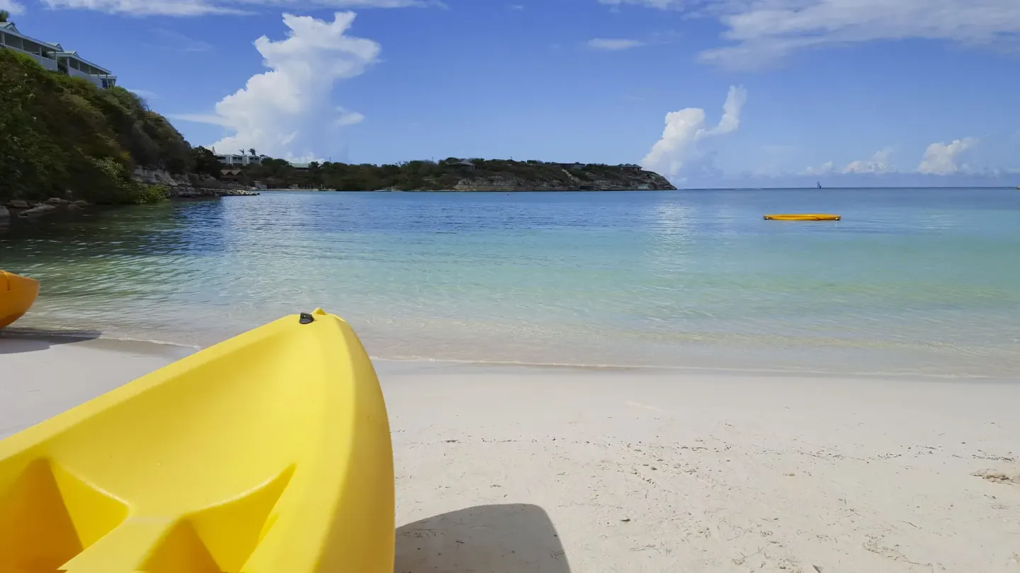 Yellow kayak on the white-sand beach and calm bay at The Verandah Antigua.