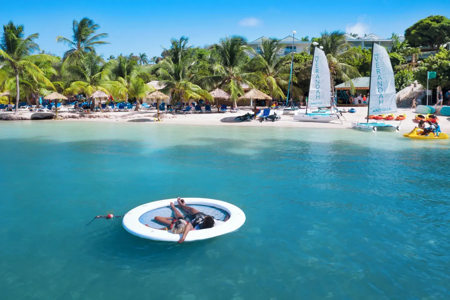 Guests float near sailboats and kayaks off the beach at The Verandah Antigua.
