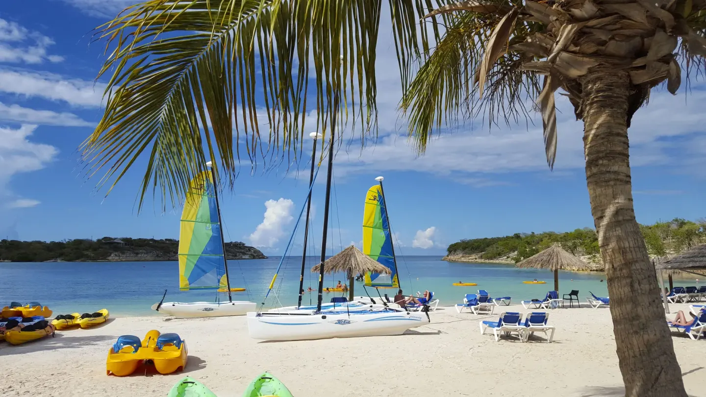Sailboats, kayaks, loungers, and palm trees on the beach at The Verandah Antigua.