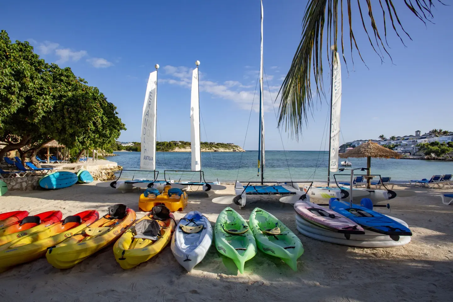 Kayaks, paddleboards and sailboats lined up on the beach at The Verandah Antigua.