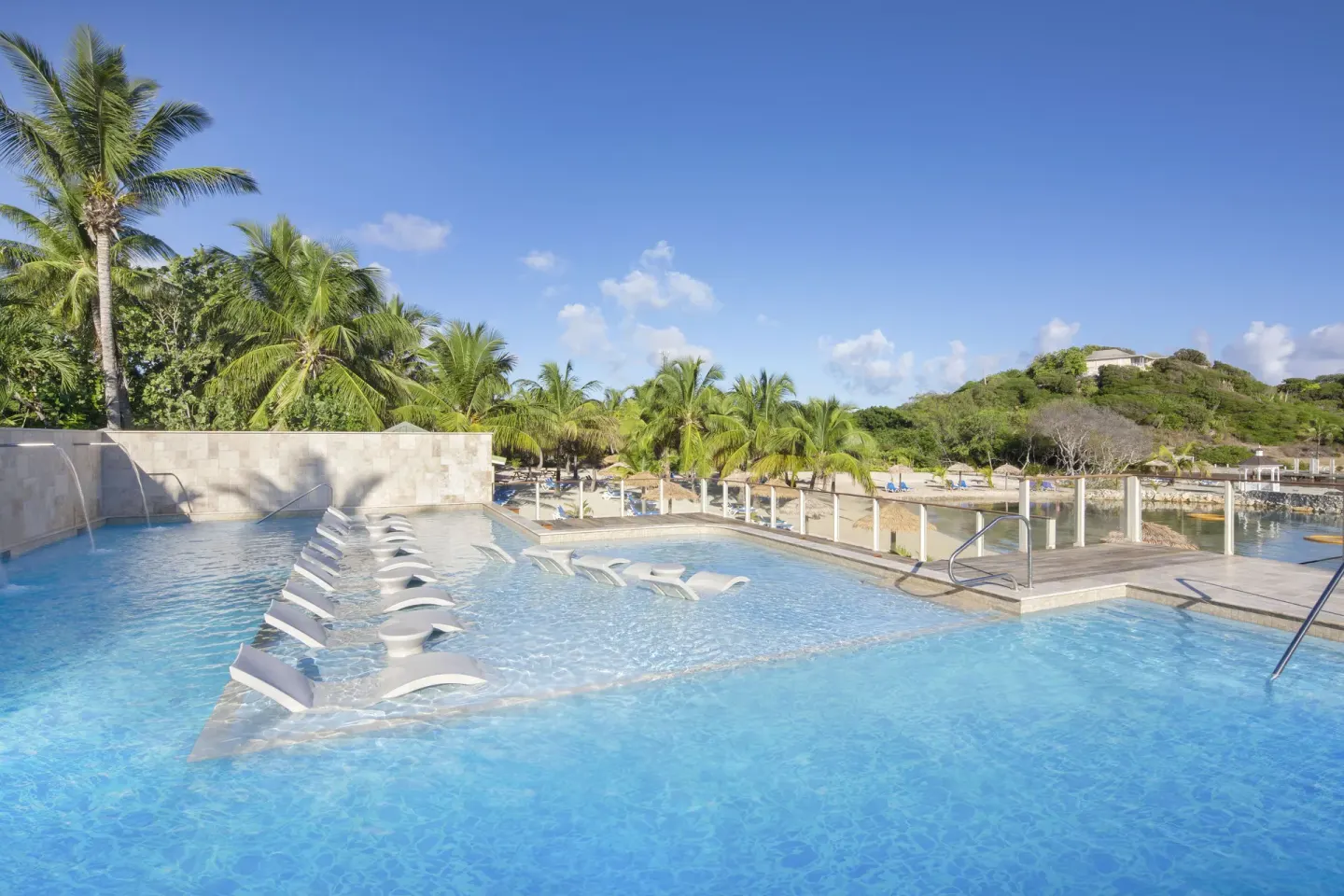 Infinity-edge pool with submerged loungers by the beach at The Verandah Antigua.