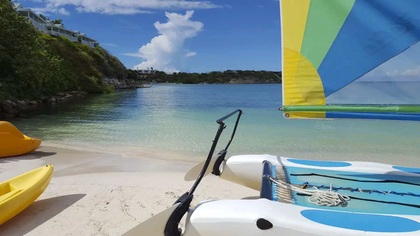 Close view of a catamaran sailboat on the beach by clear water at The Verandah Antigua.