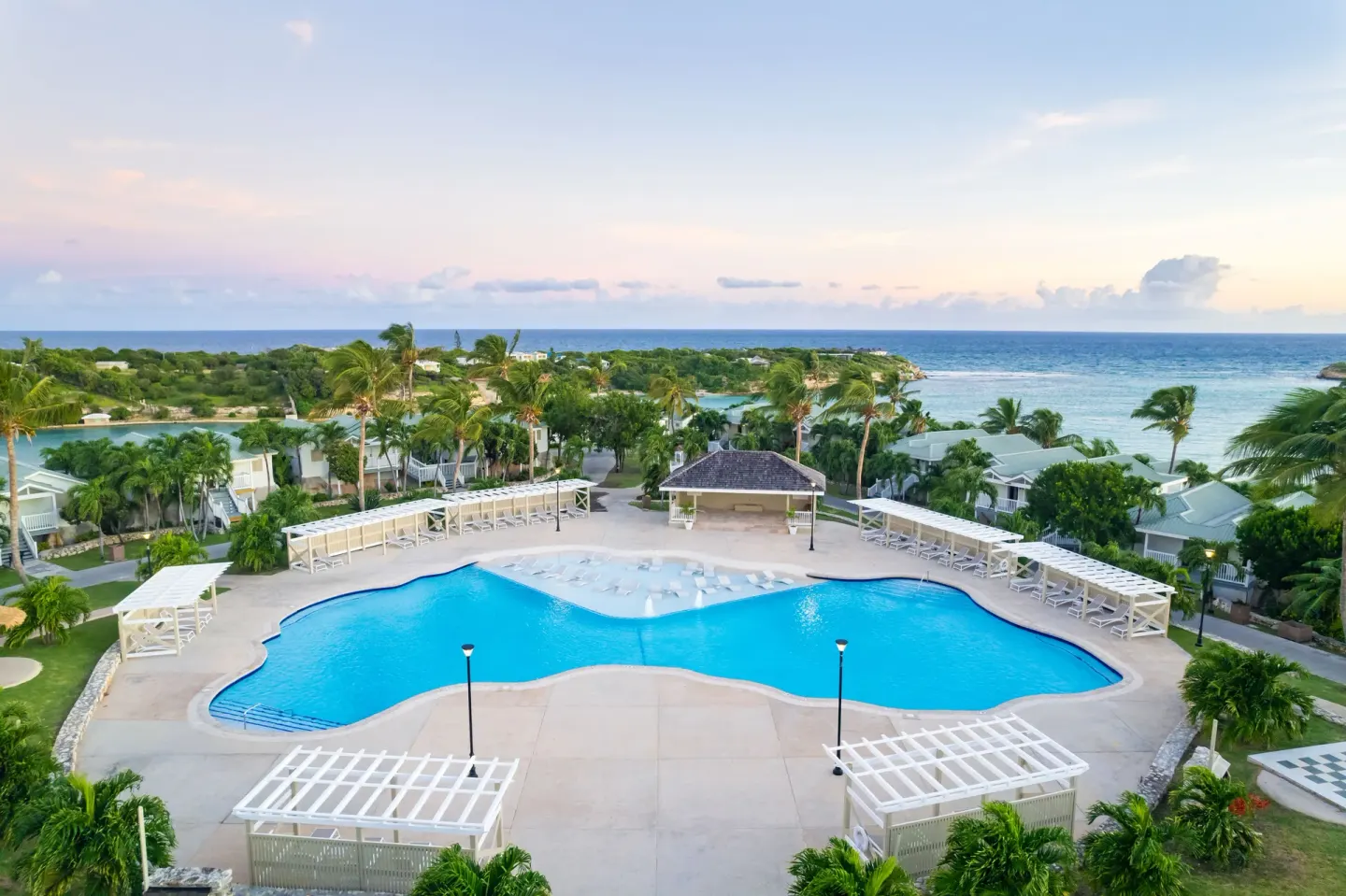 Large resort pool with ocean view and white shade structures at The Verandah Antigua.