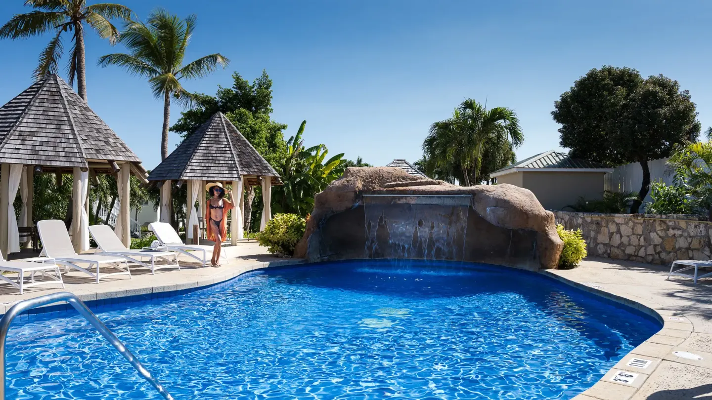 Pool with rock waterfall, cabanas, and palm trees at The Verandah Antigua.