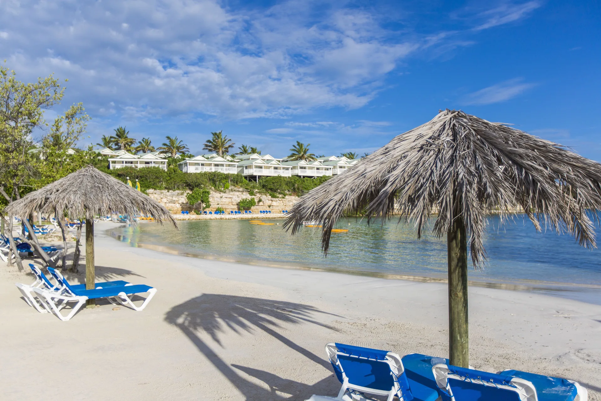 Thatched beach umbrellas and blue loungers by the bay at The Verandah Antigua.