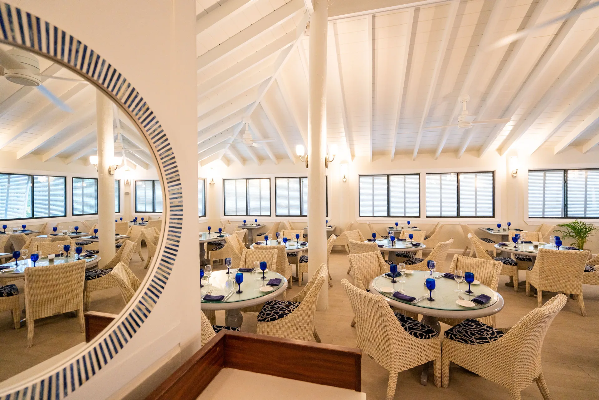 Bright dining room with wicker chairs and blue goblets at The Verandah Antigua.