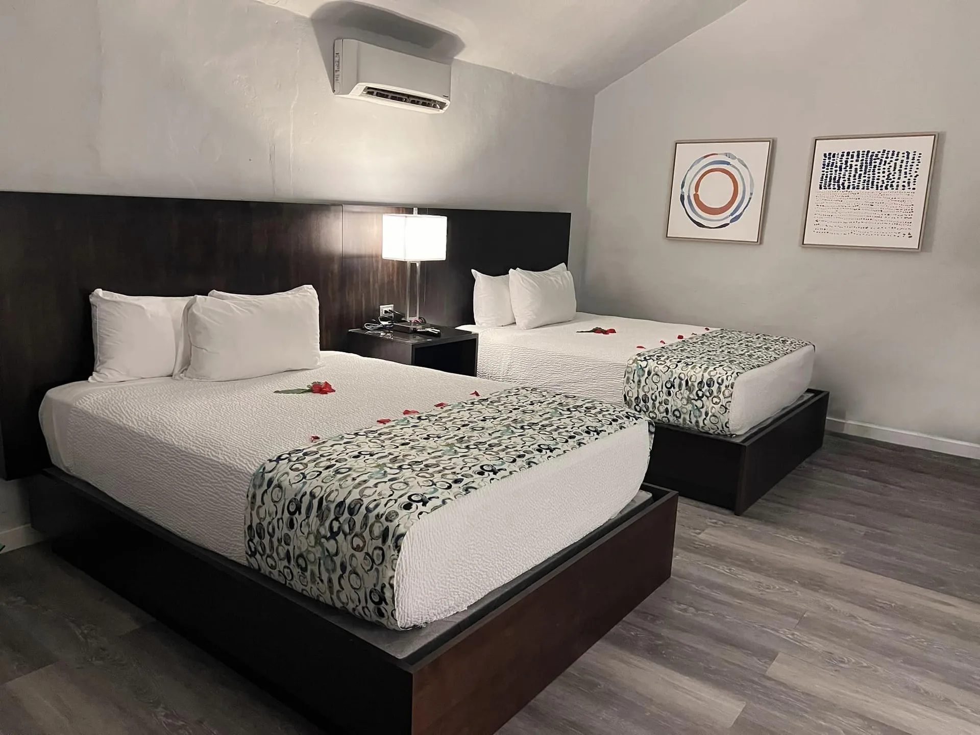 Waterfront Suite with two queen beds at The Verandah Antigua, shown with wall art and bedside lighting.