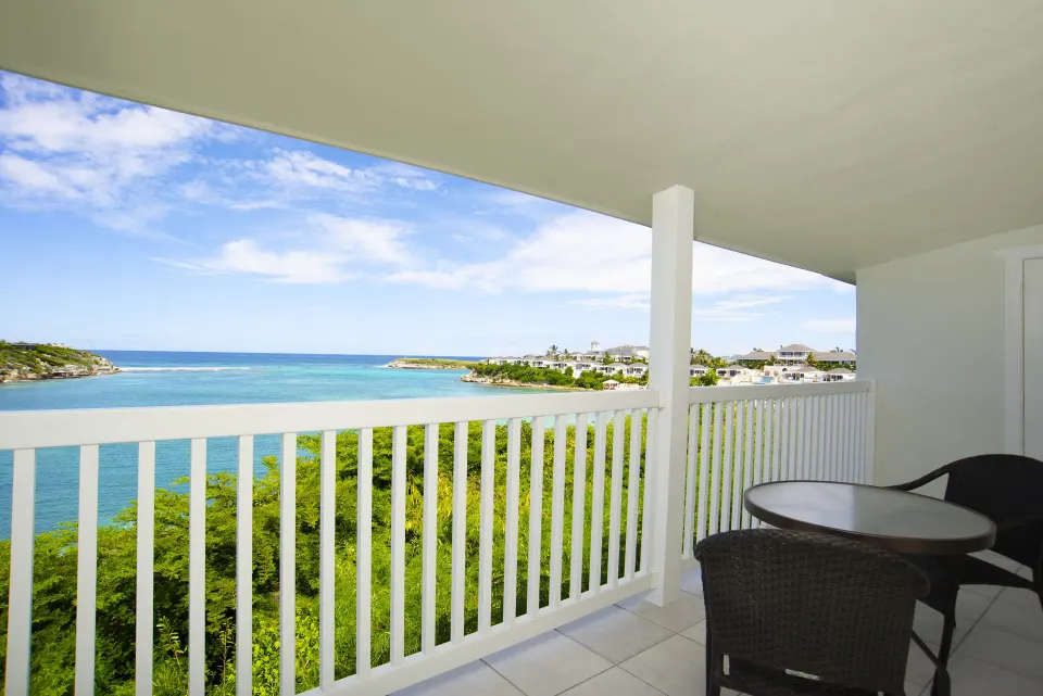 Waterfront suite balcony with table and ocean view at The Verandah Antigua.