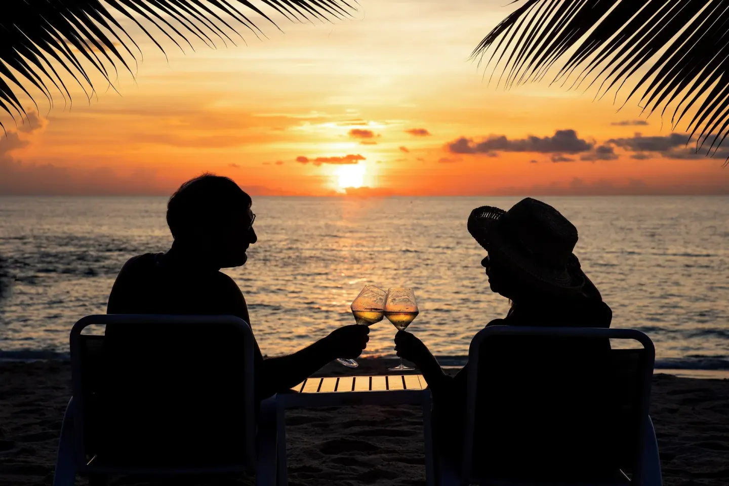 Couple toasting on the beach at sunset at The Westin Grand Cayman Seven Mile Beach Resort & Spa.
