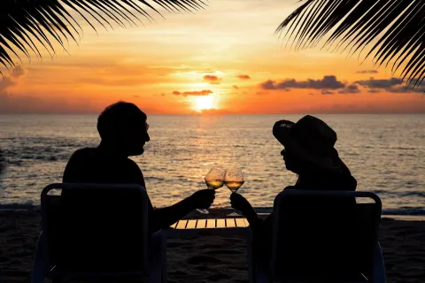 Couple toasting on the beach at sunset at The Westin Grand Cayman Seven Mile Beach Resort & Spa.