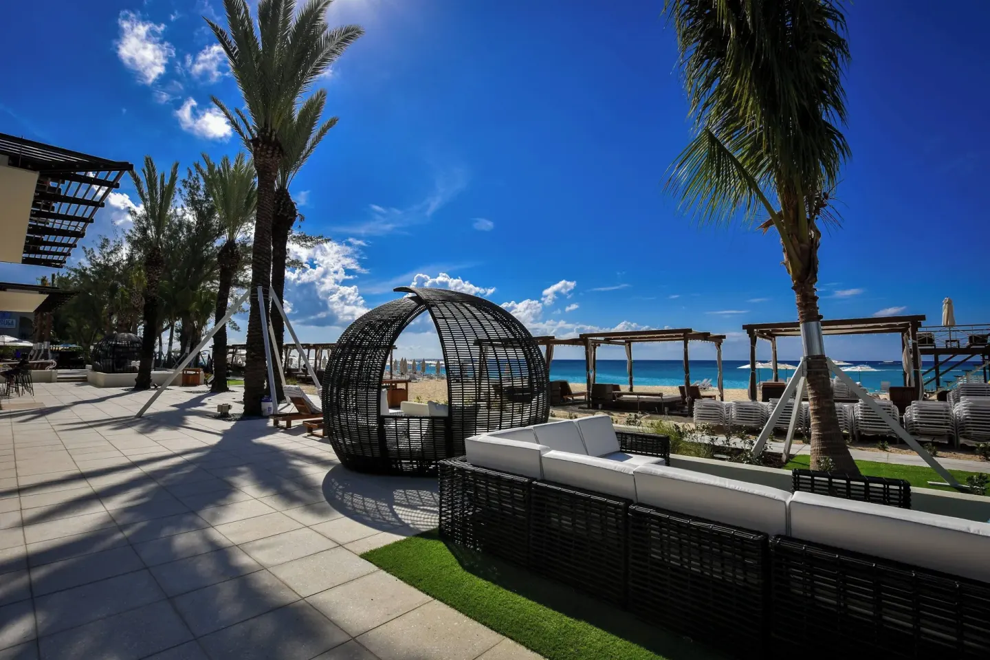 Beachfront terrace seating and palms at The Westin Grand Cayman Seven Mile Beach Resort & Spa.