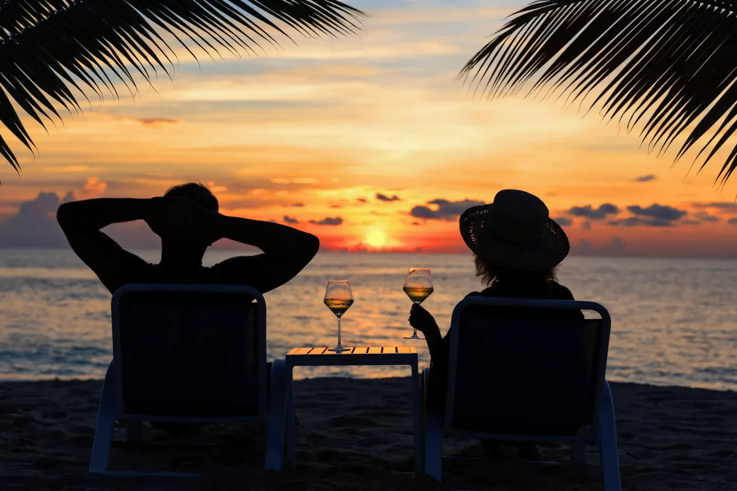 Two guests watch sunset on the beach at The Westin Grand Cayman Seven Mile Beach Resort & Spa.