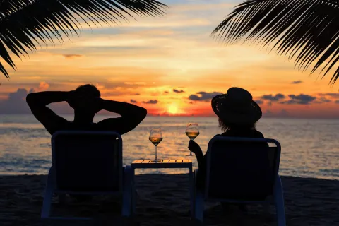 Two guests watch sunset on the beach at The Westin Grand Cayman Seven Mile Beach Resort & Spa.