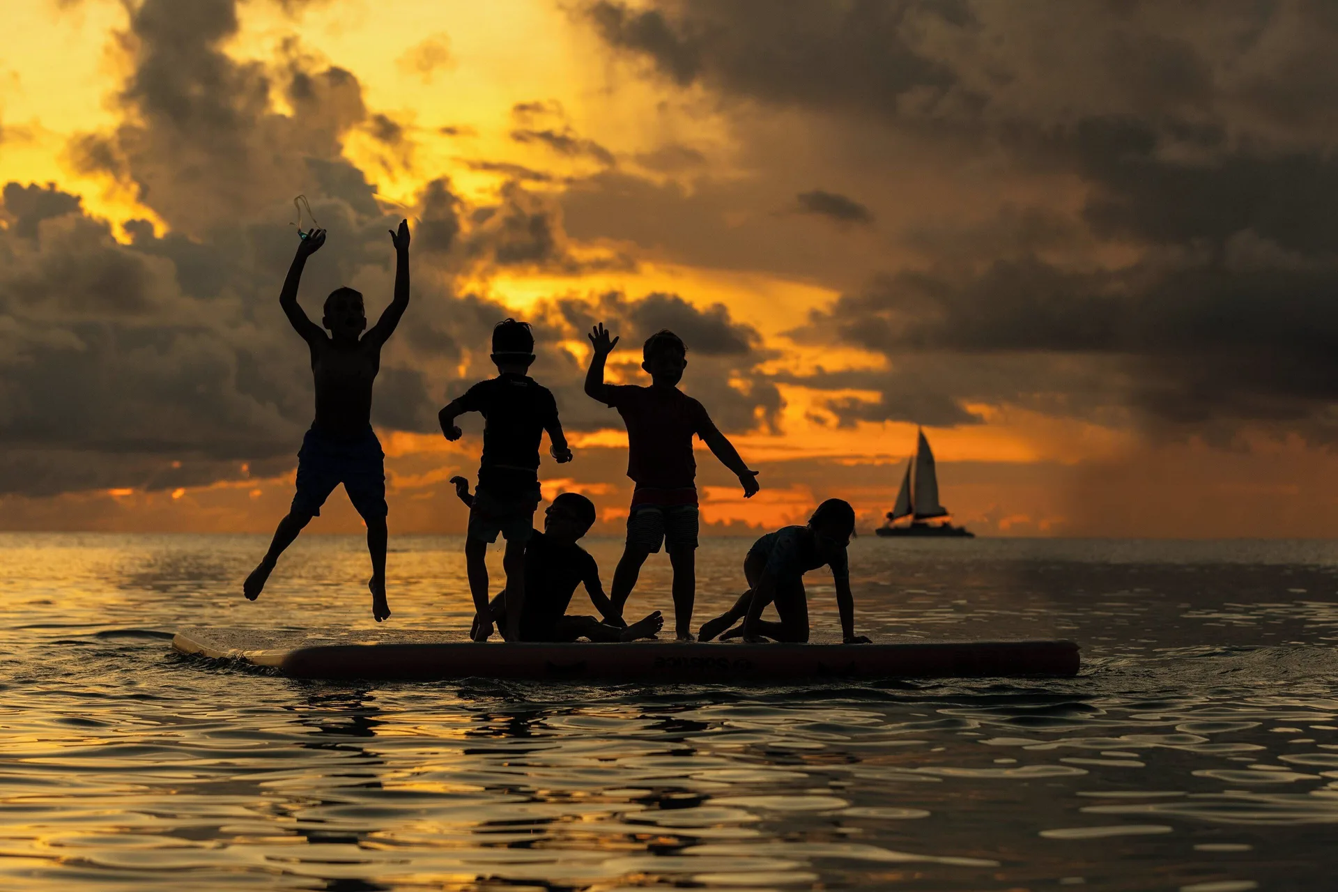 Children silhouetted on the water at sunset at The Westin Grand Cayman Seven Mile Beach Resort & Spa.