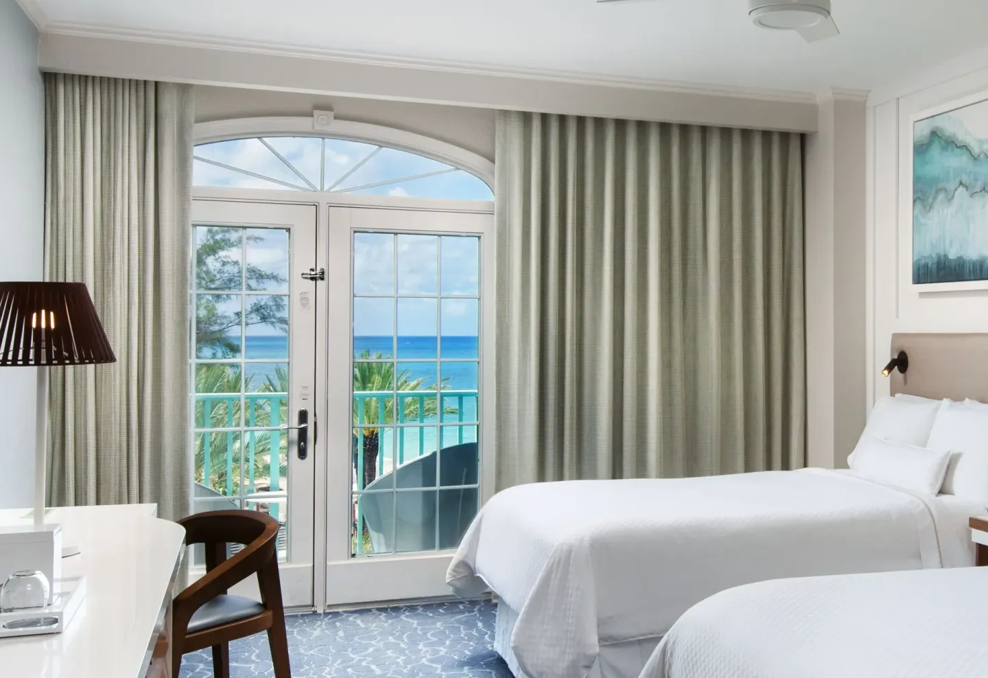 Balcony doors and two queen beds in a room at The Westin Grand Cayman Seven Mile Beach Resort & Spa.