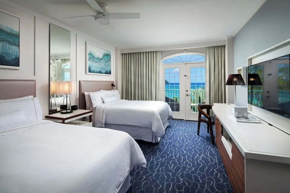 Two queen beds and balcony ocean view in a room at The Westin Grand Cayman Seven Mile Beach Resort & Spa.